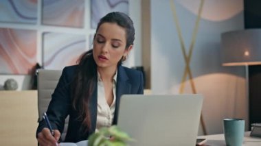 Dalgın yönetici modern dizüstü bilgisayarla yakın çekim yaparak notlar alıyor. Ciddi bir iş kadını ofisinde elinde kupayla not defterine bir fikir yazmayı düşünüyor. Düşünceli CEO iş stratejisi yaratıyor bilgisayar görünümlü 