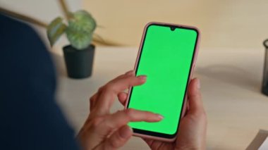 İş kadını parmakları iş yerinde yakın plan internet sörfü yapmak için kromakey akıllı telefon kullanıyor. Ofiste elinde yeşil ekran cep telefonu tutan kadın elleri dokunmatik ekrana dokunuyor. Yönetici model aygıtı üzerinde çalışıyor