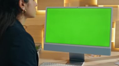 Patron Chromakey bilgisayar ekranını izliyor. Çalışma masasında oturuyor. Modern apartmandaki yeşil ekran bilgisayarında e-posta okuyan bir kadın. İş kadını çevrimiçi eğitici web sitesi görüntüleme monitöründe 