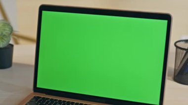 Modern yeşil ekran laptop ofis masasına yakın plan yerleştirilmiş. Açılan dizüstü bilgisayarın görüntüsü yeşil ekran monitörü şirket işi için hazır. Açık şirket işyerinde boş krom anahtar bilgisayar görüntüsü