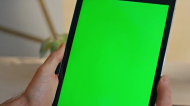 Bilinmeyen yönetici çalışma masasında oturmuş Chromakey tableti izliyor. Modern ofiste elinde yeşil ekran bilgisayar tutan bir adam. İşadamı sadece modelleme aygıtında eğitici çevrimiçi webinar arıyor