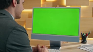 Resmi eleman yeşil ekranlı bilgisayara el hareketi yaptırıyor. Ofise yakın çekim yapıyor. Mutlu gülümseyen yönetmen çevrimiçi model monitörü konuşuyor. Patron görünümlü Chroma Key PC Sanal konferans yakınlaştırması yapıyor