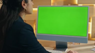 Şirketin ofisinde yeşil ekran bilgisayarı kullanan bir iş kadını. Esmer bayan yönetici krom anahtar bilgisayarda tek başına çalışıyor. Özel kabinede çevrimiçi konferans bekleyen meşgul çalışan görünümlü model monitörü 