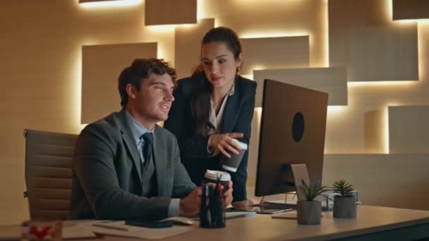 キャビネットバーオのクローズアップでコンピュータ画面を見ている遅い同僚 新しいプロジェクトでコーヒーを手がけるポジティブなビジネスマン 陽気な同僚カップルは夜の職場でPcを議論する — ストック動画
