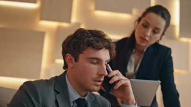 Odaklanmış işadamı akıllı telefonu arıyor. Bej dolabı kapatılıyor. Tablet tutan endişeli sekreter kadın patrona bakıyor. Cep telefonu görüşmesini bitiren deli adam iş evraklarını duygusal olarak fırlatıyor.