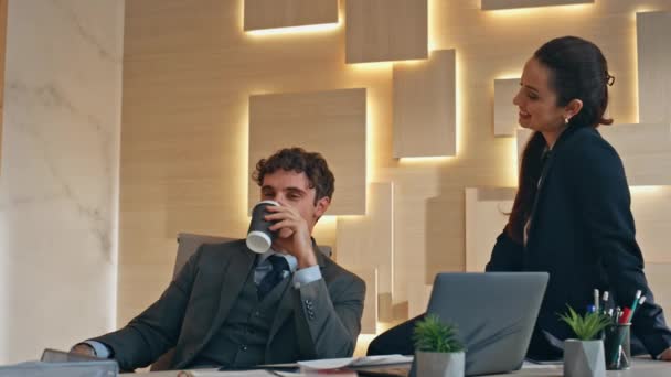 深いバーボのクローズアップで休憩を楽しんでいる企業カップル ビジネスパートナーは ベージュキャビネットで話すコーヒーを飲む労働者 カップボードカップを持っているビジネスマンを座る 2人の同僚が一緒に休んでいる — ストック動画