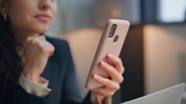Kadın elleri cep telefonuyla modern ofiste yakın çekim yapıyor. İş meselelerini çözmek için akıllı telefonu kullanan kendine güvenen bir iş kadını. Mutlu zarif bayan patron telefon ekranında dinleniyor. 