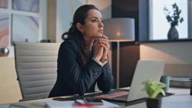 Lüks ofislerde dizüstü bilgisayarı olan düşünceli CEO masası. Gülümseyen bayan girişimci kameraya bakıp bilgisayar masasında tatmin oluyor. Esmer iş kadını kabinede iş yapmayı düşünüyor 