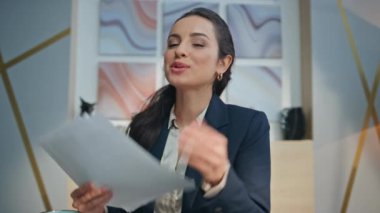 Gülümseyen iş kadını ofiste video görüşmesini yakından selamlıyor. Profesyonel yönetici neşeli bir sohbete girişiyor. Kontrat görüşünü gösteriyor. İnternet koçu elinde web sohbetini açıklayan belgeler tutuyor