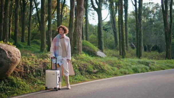 旅客们站在路边 提着手提箱 在秋天的森林里安静下来 冒险犯难的女人在林子里等着 时尚的女探险家 准备去野外探险 — 图库视频影像