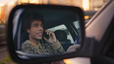 Sürücü, şehir manzarası ile arabanın yan aynasında akıllı telefonlardan konuşuyor. Latin bir adam gezici sohbetten zevk alıyor. Yansıması neşe veriyor. Gülümseyen erkek hippi otomobilde arama yapıyor..