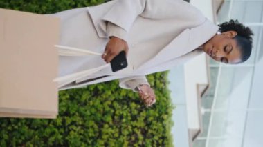 Dikey alışveriş torbalarıyla caddede yürüyen zarif bir kadın. Gülümseyen siyah saçlı kız elinde anahtarlarla eve gidiyor. Afro-Amerikalı iş kadını akşamdan zevk alıyor. Zengin yaşam tarzı konsepti