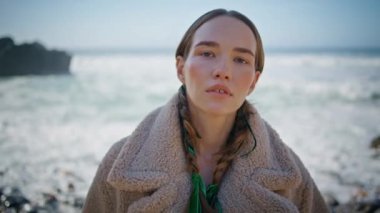 Güneşli sahile poz veren sakin kadın portresi. Örgü örüp okyanus kıyısını palto içinde dinlendiren manken. Yansıtıcı sakin kız köpüren dalgalara bakıyor. Güzel kâşif kış kumsalında tefekkür ediyor..