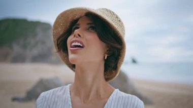 Gülen kadın hasır şapkalı deniz kıyısından zevk alıyor. Yazın plajda dinlenen seyahat kızına ilham verdi. Şık, mutlu bir gezgin kayalık sahilde dinlenirken doğayı düşünüyor. Deniz kenarında tatilde olan harika bir kadın..