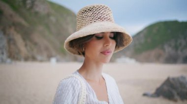Yazlık kadın hasır şapkalı kumsalda poz veriyor. Çekici kız deniz kıyısında dinleniyor. Kayalık, ıssız deniz kıyısına bakıyor. Havalı gezgin deniz kenarında hafta sonunun tadını çıkarıyor. Sakin turist yalnız başına dinleniyor..