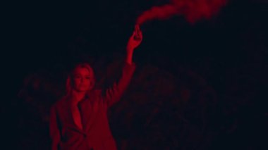 Feminist, karanlık sahilde sis bombası tutuyor. Kırmızı ışıkta duman bulutu içinde kendine güvenen bir kız. Gece vakti takım elbiseli, renkli el bombası sallayan ciddi ve güzel bir sarışın. Özgürlük performansı kavramı.
