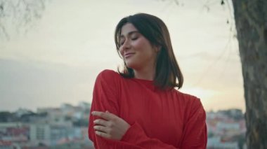 Tasasız kız doğanın tadını çıkarıyor. Gün batımında tek başına şehir parkında dikiliyor. Yakın çekim. Akşamları dinlenme yerinde dinlenen güzel, sakin bir kadın. Mutlu gülümseyen bayan ormanda huzuru hissediyor.