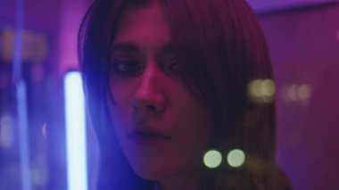 Sigara içen kadın neon şehirde poz veriyor. Muhteşem modaya uygun model. Haftasonu, aydınlık eğlence parkında dinleniyor. Romantik, dingin esmer, gece hayatının tadını çıkarıyor. Şenlikli moda kadını 