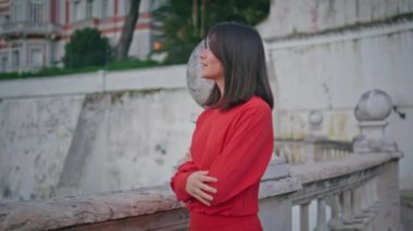 Rüya gibi yürüyen şehir, yakın plan. Genç, romantik bir kadın kameraya bakıyor ve sakin bir anın portresini çekiyor. Kırmızı elbiseli çekici bir bayan yalnız başına poz veriyor, çeşme meydanında geziniyor. İnsan yaşam tarzı 