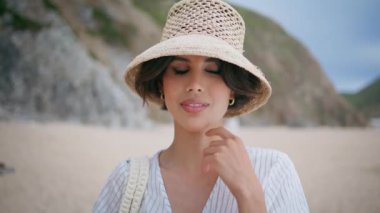 Plaj adasında dinlenen romantik kız portresi. Gülümseyen seyahat eden kadın tek başına deniz kenarında tatilin tadını çıkarıyor. Kayalık sahilde poz veren güzel bir turist. Yaz tatilinde şık bir bayan..