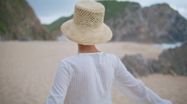 Yazın plajda dönen kaygısız bir kadın. Gülümseyen gezgin kız kameraya bakıp tatildeki kayalık sahilin tadını çıkarıyor. Çekici, mutlu bir bayan, tek başına dinleniyor. Neşeli turist okyanusta dinleniyor.