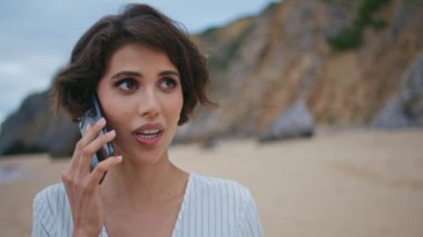Kumsalda cep telefonuyla konuşan esmer bir kadın. Sakin bir kadın tatilde partneriyle birlikte sahilde keyif çatıyor. Güzel kaygısız kadın deniz kenarını keşfediyor dışarıda cep telefonuyla konuşuyor..