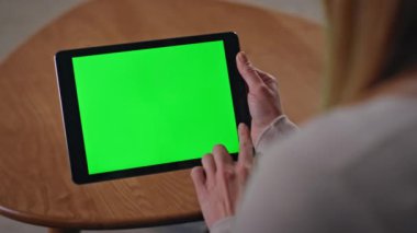 İş kadını elleri yeşil ekran tablet uygulamasına bakıyor. Krom tuş pedi bilgisayarı kullanarak çevrimiçi çalışan tanınamaz bir serbest çalışan. Meçhul kız evin içinde oyuncak eşyalara dokunuyor..