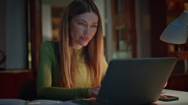 Akşam apartmanında çalışan iş kadını. Kapatın. Çekici bir kadın gece evde bilgisayarında iş e-postalarını okuyor. Karanlık, ücra bir iş yerinde serbest çalışmanın mutluluğu..