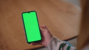 Akıllı telefon kullanıcısı, evdeki daireyi kapatırken yeşil ekranı kaydırıyor. Kadın elleri krom tuşlu cep telefonuna dokunuyor internet uygulamasını tarıyor. Haberleri model cep telefonundan izleyen tanınmayan kız