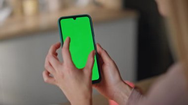 Yeşil ekran akıllı telefonu olan bir kadın evde sosyal medyayı seyrediyor. Yeşil ekran cep telefonuna dokunan tanınmayan bir kız. Bilinmeyen ev hanımı krom anahtarlı cep telefonu fotoğraflarına bakıyor..