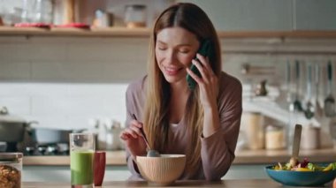 Telekız, ev mutfağında kahvaltının tadını çıkar. Gülücükler saçan güzel bir kadın akıllı telefonlardan bahsediyor evde yemekleri kaseye karıştırıyor. Mutlu, rahat bir bayan hafta sonu cep telefonuyla konuşur..