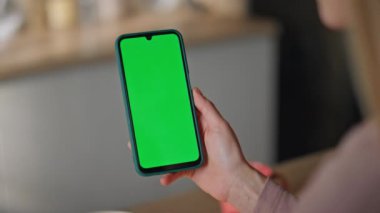 Kız parmakları dairede cep telefonunu kaydırıyor. Çevrimiçi alım yapan yeşil ekran akıllı telefonu araklayan tanınmamış bir kadın. Bilinmeyen iş kadını kroma anahtarlı cep telefonu kullanıyor..