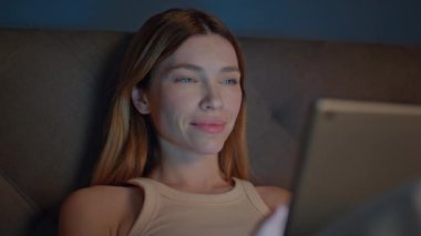 Uykucu kız kitap okuyor. Karanlık dairedeki yatak odasını kapatıyor. Yatma vakti geldiğinde tablet ekranda gülümseyen rahat kadın. İnternette internette internette gezinen mutlu kadın sörfü uygulaması..