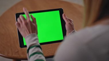 Çevrimiçi işçi, dokunmatik ekranı gösteren bir tablet kaydırıyor. Dairenin krom anahtarı üzerinde çalışan tanınmayan serbest çalışan biri. Kız elleri yeşil ekranlı bilgisayara dokunuyor..