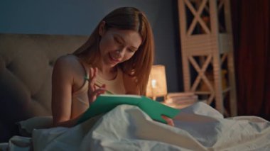 Romantik kız kitap yazıyor. Rahat bir akşam yatağı hazırlıyor. Yatma vakti elinde kalemle günlüğe not alan mutlu genç bir kadın. Gülümseyen çekici kadın yazar defterde kompozisyon oluşturuyor..