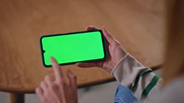 Kadın elleri krom tuşlu akıllı telefona dokunuyor ve evde video izliyor. Yeşil ekranda cep telefonunu çalan tanınmayan bir kız. İnternet uygulama telefonundan bilinmeyen bir bayan çevrimiçi alımlar seçiyor.