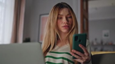Kız serbest çalışan akıllı telefon ekranı dairede dizüstü bilgisayarda çalışıyor. Kendine güvenen uzaktan çalışan cep telefonu oturma koltuğundan maaş bildirimi alıyor. SMS okuyan rahat iş kadını.