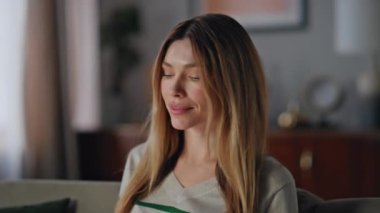 Rahat iş kadını cep telefonu mesajı okuyor modern rahat oturma odasını kapatıyor. Güzel sakin bir kadın akıllı telefon uygulamasını ev koltuğunda araştırıyor. Hayalperest kız online alışverişleri düşünüyor..