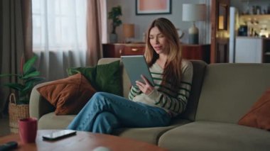 Tablet okuyan mutlu kadın, rahat bir kanepede dinleniyor. Gülümseyen çekici bir kız bilgisayardaki bankacılık uygulamasında koltukta oturuyor. Pozitif kadın evdeki internet iletişimini seviyor..