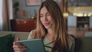 Modern apartmandaki tablette internette serbest sörf yapan biri. İnternette e-posta mesajı okuyan çekici bir kadının portresi. Sakin mutlu kız internet ürünlerini seçiyor..