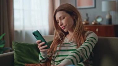 Oturma odasında cep telefonu mesajı okuyan hayal kırıklığına uğramış bir kadın. Genç bayan evde oturan akıllı telefon mesajlarından memnun değil. Çekici bir serbest yazar telefonda hayal kırıklığını ifade ediyor.