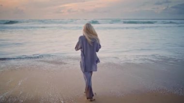 Rahat bayan sahilde eğleniyor. Gün batımında kumlu sahilde yürüyen mutlu sarışınlar. Yaz tatilinde tropik plajlara çıkan deniz dalgalarına hayran olan güzel bir kadın. Resimli deniz doğası.. 