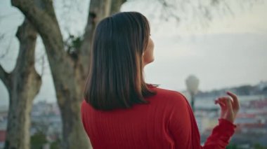 Esmer model, saç stilini düzeltiyor. Park manzarasını tek başına değiştiriyor. Kırmızı elbiseli kadın şehir manzarasına bakıyor. Samimi bahçedeki kamerayı kapatıyor. Çekici, rahat model kız haftasonu akşamının tadını çıkarıyor.
