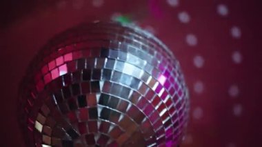 Kapalı disko topu gece partisinde sallanıyor. Aynalı küre, modern gece kulübü atmosferini şık bir ışıltıyla yansıtıyor. Diskotek ekipmanları ve kulüpte dönen yansıyan ışıklar. Ayna diskotopu dönüyor