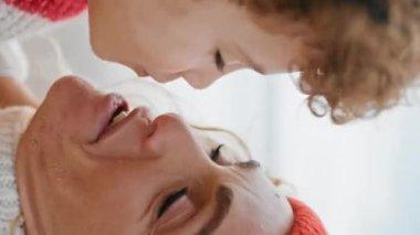 Mutlu çocuk annesini öpüyor ve okyanus kıyısında birlikte eğleniyor. Komik kıvırcık çocuk annesiyle dışarıda dikey olarak eğleniyor. Sadık ebeveyn kucaklaşması özenli sevgiyi ifade eder. Anneler Günü