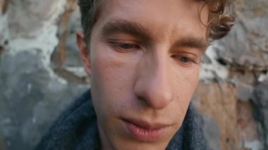 Üzgün adam rüzgarlı bir günde kale duvarına poz veriyor. Depresyondaki sarışın adam aşağıya bakıyor ve sorunları tek başına yakından inceliyor. Model düşünceli.