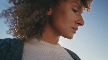 Üzgün kadın, arka planda gökyüzünün yakın plan olduğunu düşünüyor. Kıvırcık, güzel model, mesafeli görünüyor, deniz melteminin tadını çıkarıyor. Afrikalı Amerikalı kız rüzgarlı saçlar