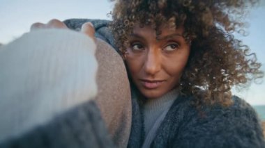 Deniz kıyısını kucaklayan yakın bir çift. Rahatlamış etnik insanlar birlikte güneşli bir günün tadını çıkarıyorlar. Sakin kadın mesafeyi arıyor, bilinmeyen adama sarılıyor.