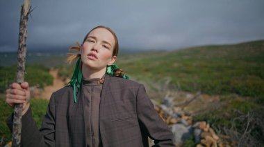 Çubuk portreyle Summer Hill 'e poz veren kız. Bulutlu bir günde dağlara tırmanan çekici bir manken. Güzel genç bayan yeşil sakin manzaraya bak. Seyahat eğlence konsepti