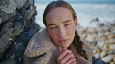 Moda kadını portrede plaja poz veriyor. Okyanus kıyısındaki kamerada çekici bir gezgin. Saçları örgülü, sakin, şık bir kız haftasonu sahilde eğleniyor. Boş zaman konsepti.